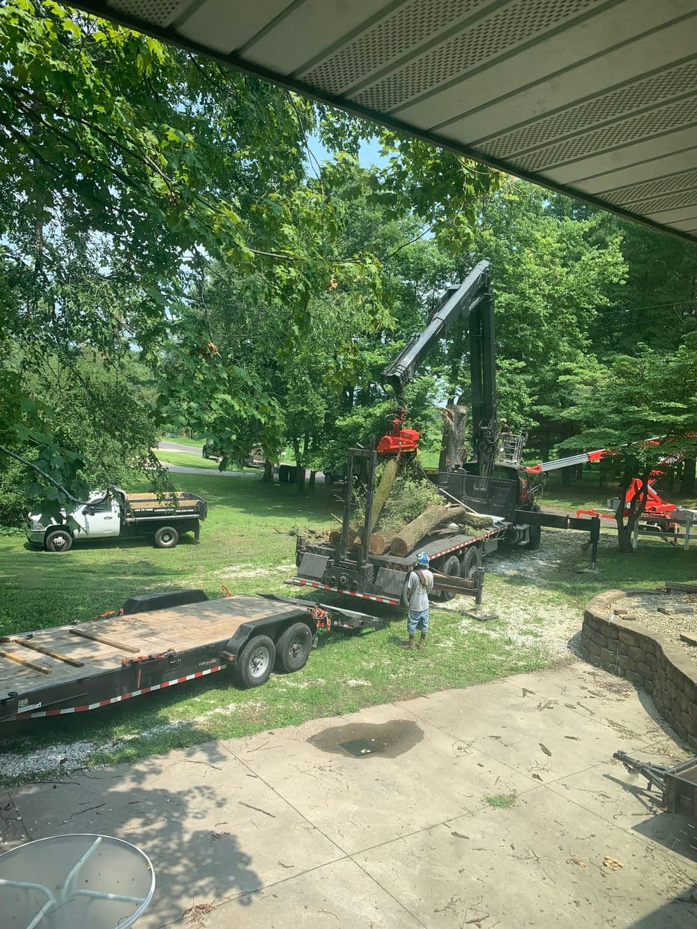 Tree removal equipment in action with workers and trucks in a residential area.