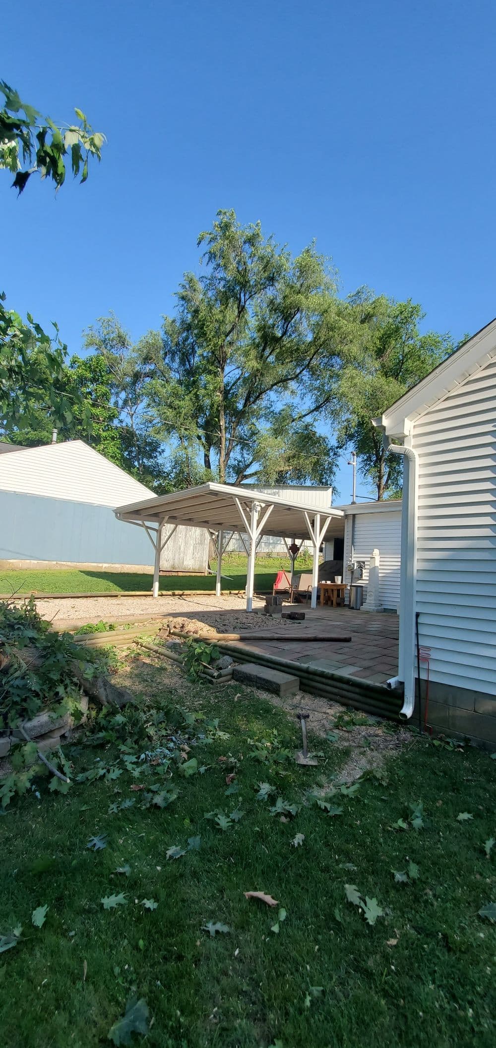 Backyard view featuring a wooden pavilion, grassy area, and a clear blue sky.